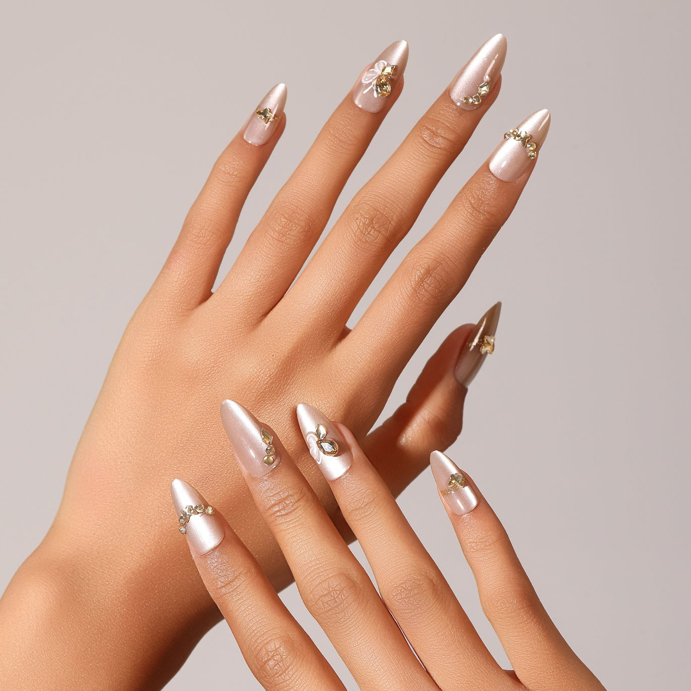 Hand wearing Sky Dance champagne pearl almond press-on nails with delicate gold embellishment