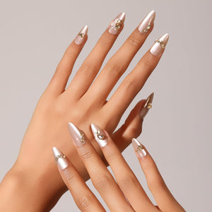 Hand wearing Sky Dance champagne pearl almond press-on nails with delicate gold embellishment