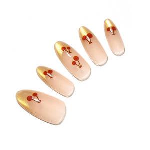 Cherry Spark Nails medium almond nude press-on nails with gold French tips and cherry accents 30-piece set