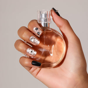 Close-up Gloss Bloom nude and black square press-on nails with silver metallic flower accent high gloss