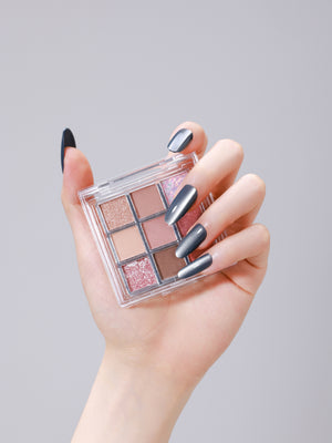 Hand wearing Smoky Quartz long oval smoky gray cat eye press-on nails holding makeup palette