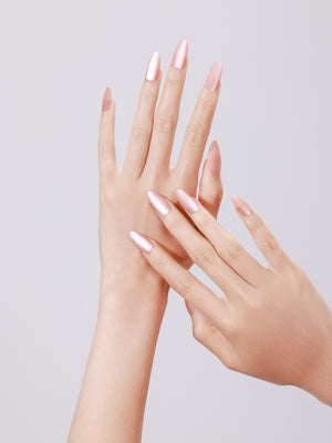 Hand wearing Soft Bloom long stiletto glazed nude press-on nails with rhinestone cuticle accent