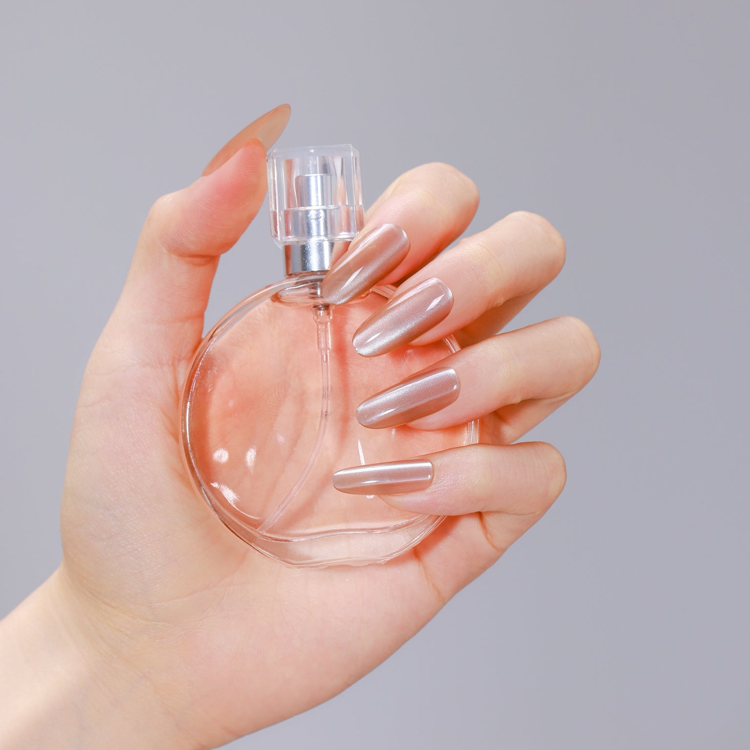 Hand wearing Moonlit Beige long oval beige nude press-on nails with glossy gel finish