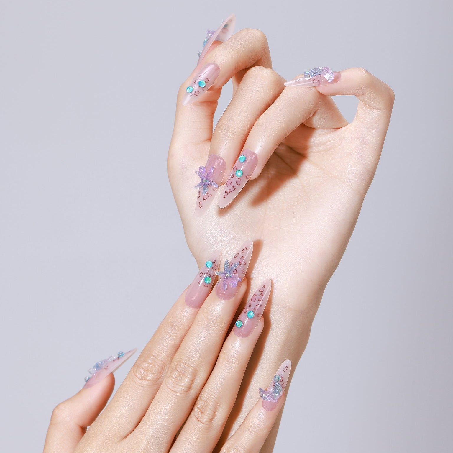 Hand wearing Star of the Tide long almond nude jelly press-on nails with turquoise gem accents