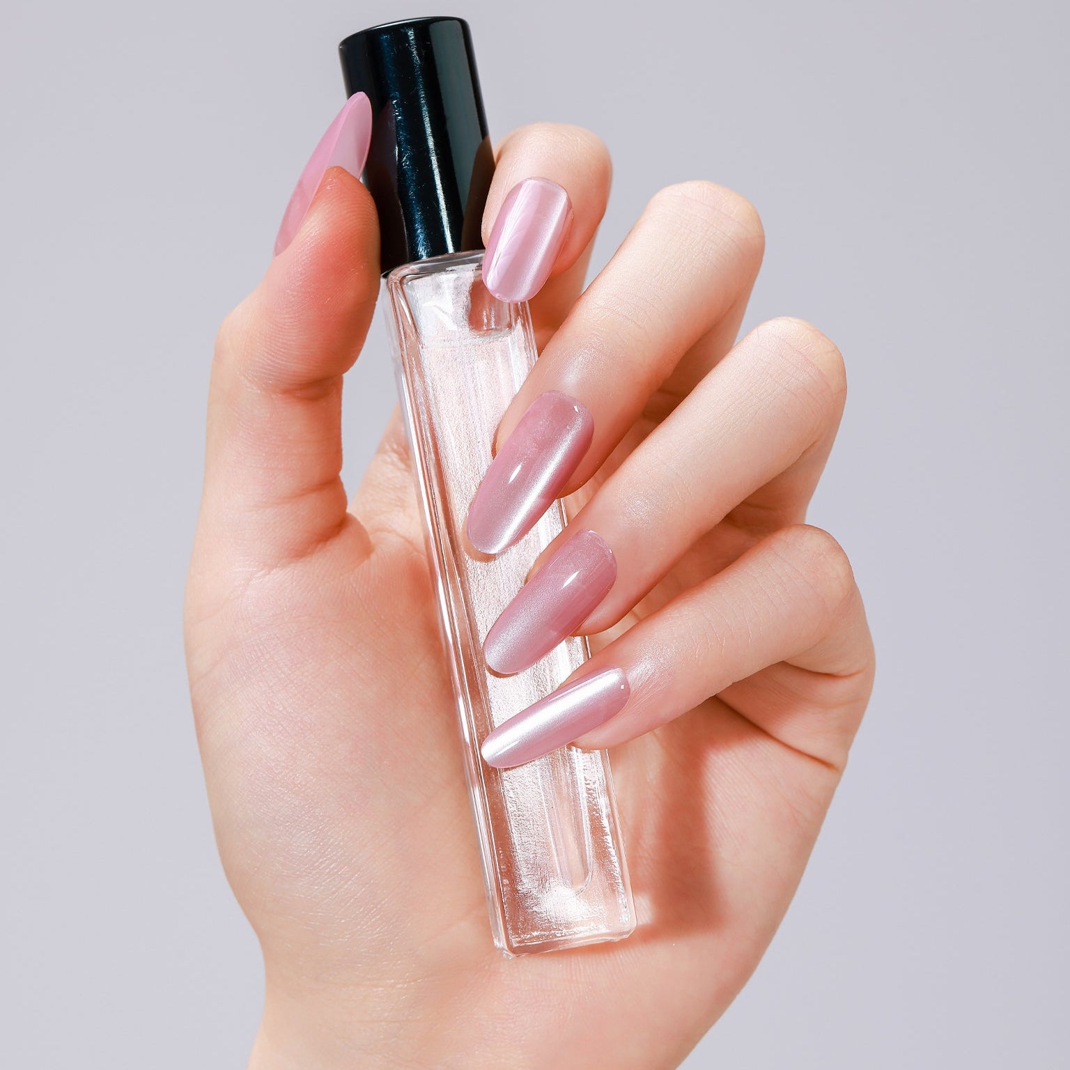 Hand wearing Pink Cloud long oval soft pink press-on nails with glossy gel finish