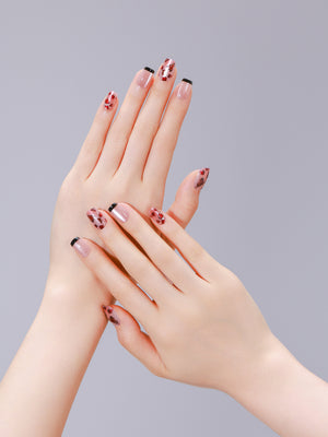Hands wearing Shadowed Rose leopard French square press-on nails with nude base and black tips