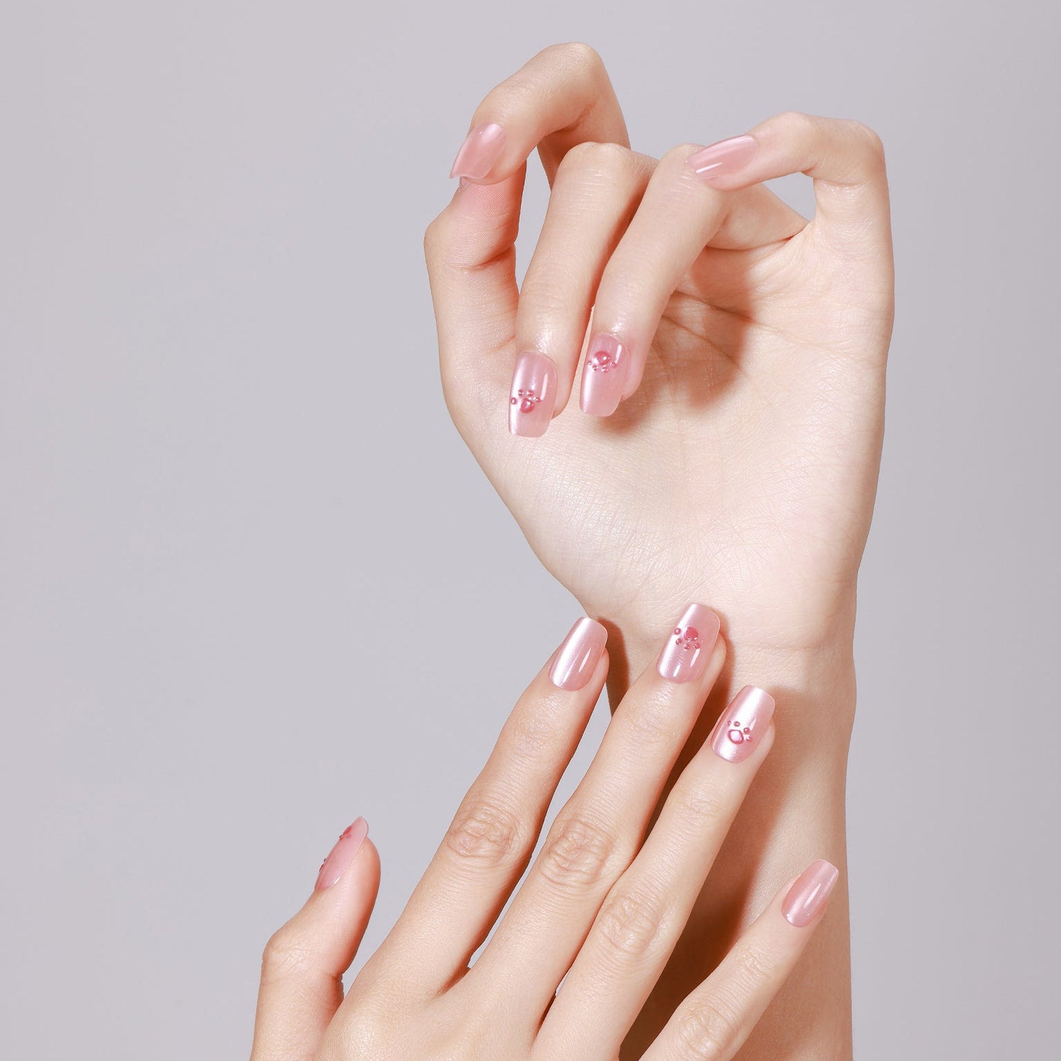 Hand wearing Pawfectly Peachy medium square peach pink paw print press-on nails with glossy finish