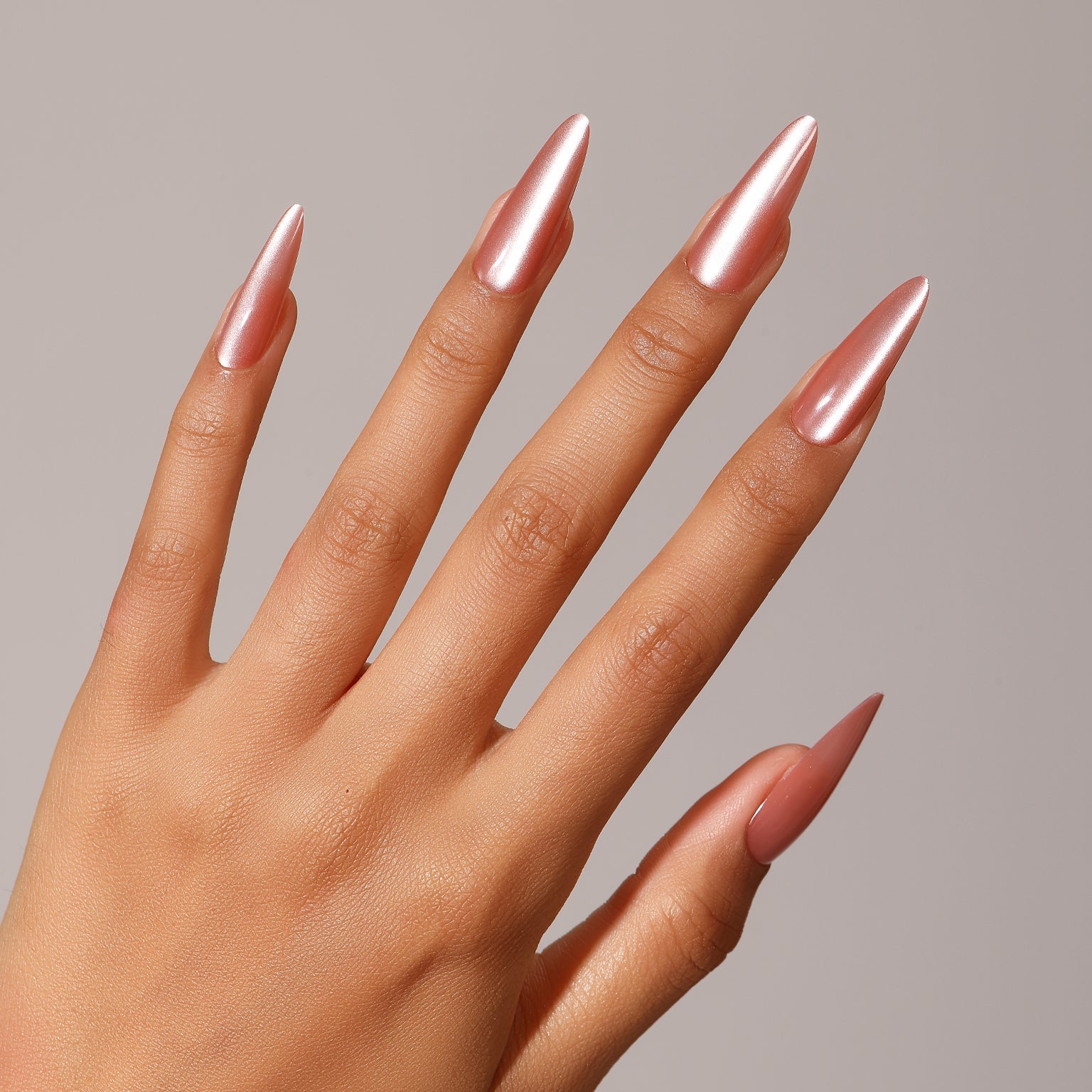 Hand wearing Pink Lady long stiletto rose chrome press-on nails mirror finish manicure
