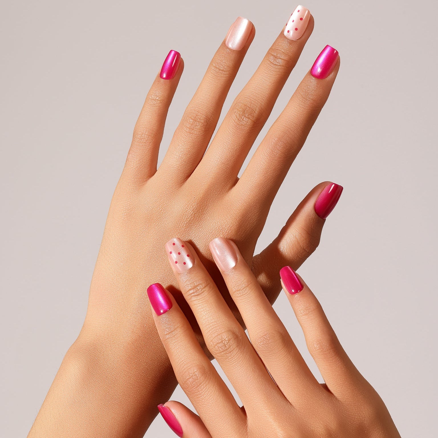 Hand wearing Poppin Rose glossy pink chrome press-on nails with pearl accent and micro dot nail art