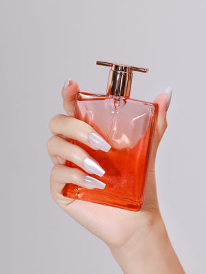 Hand holding perfume bottle with Ice Cold long coffin icy silver white press-on nails