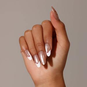 Close-up Blushing Valentine blush nude French tip press-on nails glossy finish with red sprinkle details