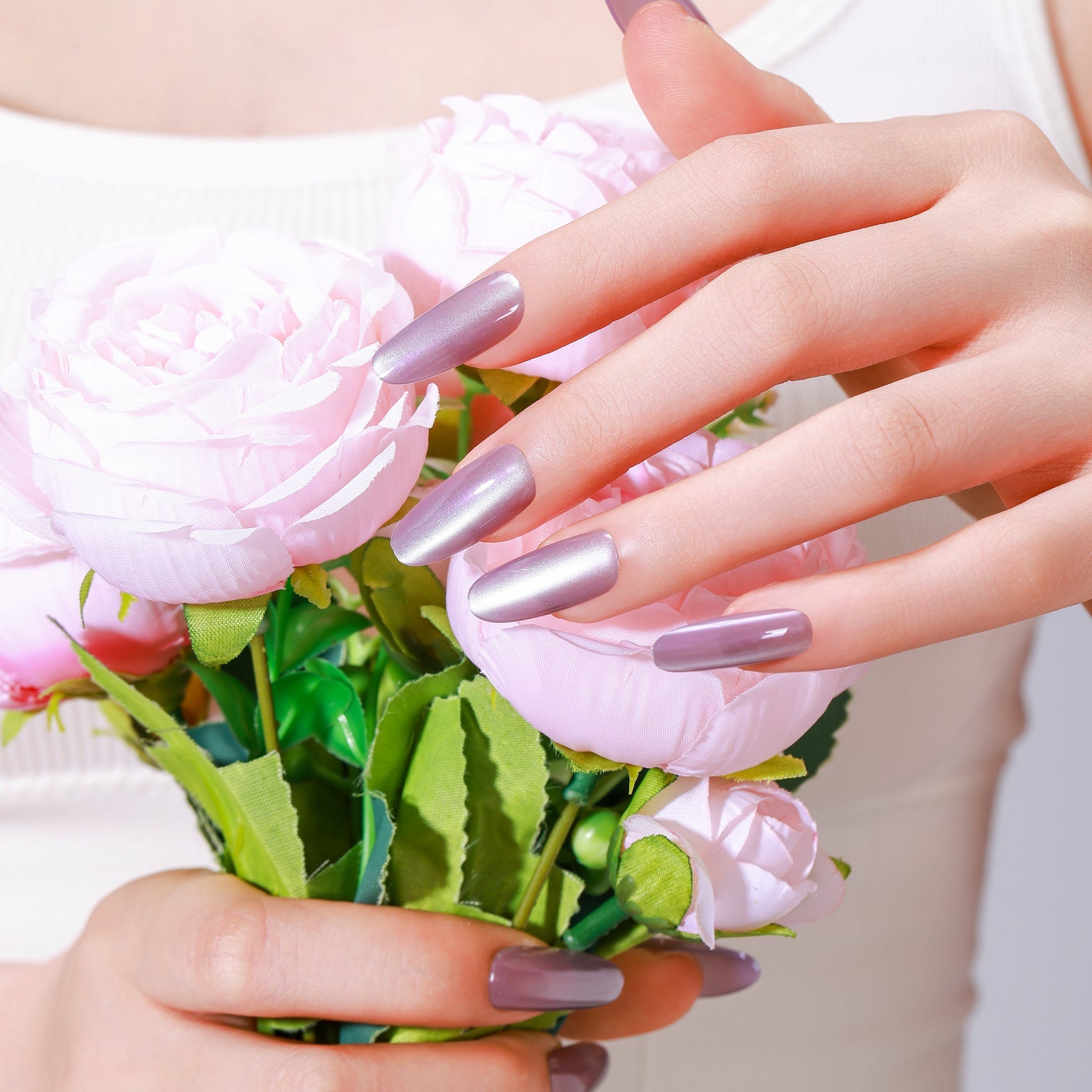 Hand holding flowers wearing Velvet Dream long oval lavender chrome press-on nails with glossy gel finish