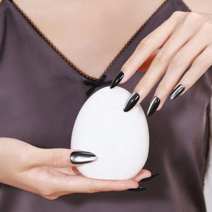 Hand wearing Noir Eclipse long almond glossy black chrome press-on nails reflective metallic shine