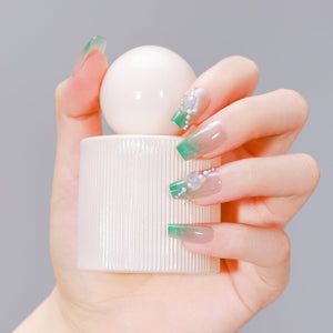 Hand holding perfume bottle wearing Garden Grace long coffin green French tip nails with 3D butterflies