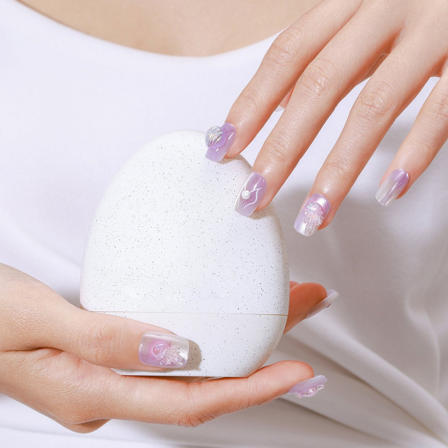 Hand wearing Ocean Princess mermaid-inspired press-on nails with pastel lilac ombré and 3D pearl accents