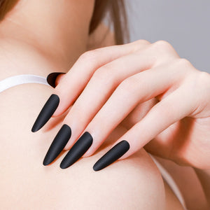Hand wearing Noir Nights long oval matte black press-on nails with velvety gel finish