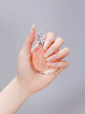 Hand wearing beige long oval peach nude press-on nails made from PMMA acrylic