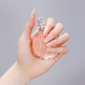 Hand wearing beige long oval peach nude press-on nails made from PMMA acrylic