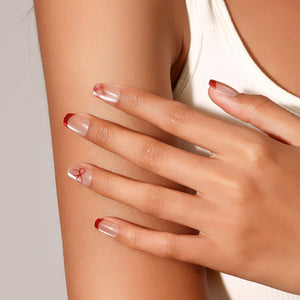 Hand wearing Garnet Bow red French tip bow press on nails for holiday look