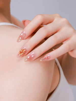 Hand wearing Firework Bless nude gold firework almond press on nails with gold shimmer bursts