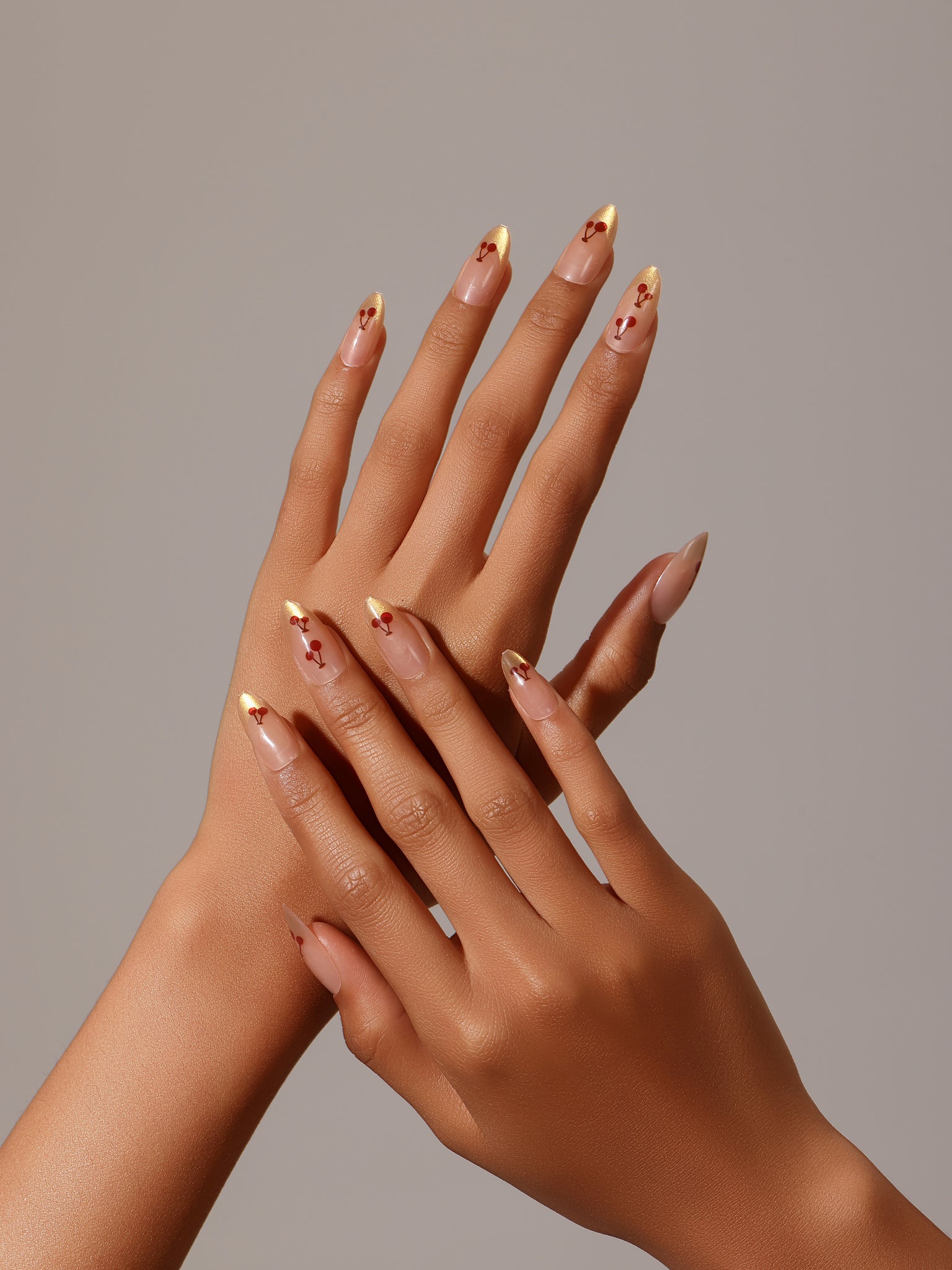 Full set showing Cherry Spark Nails nude and gold French tip press-on nails with cherry design