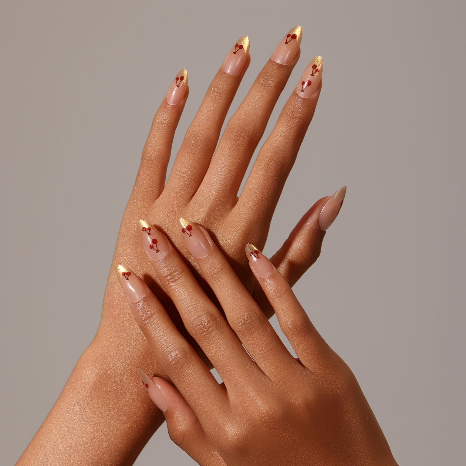 Full set showing Cherry Spark Nails nude and gold French tip press-on nails with cherry design