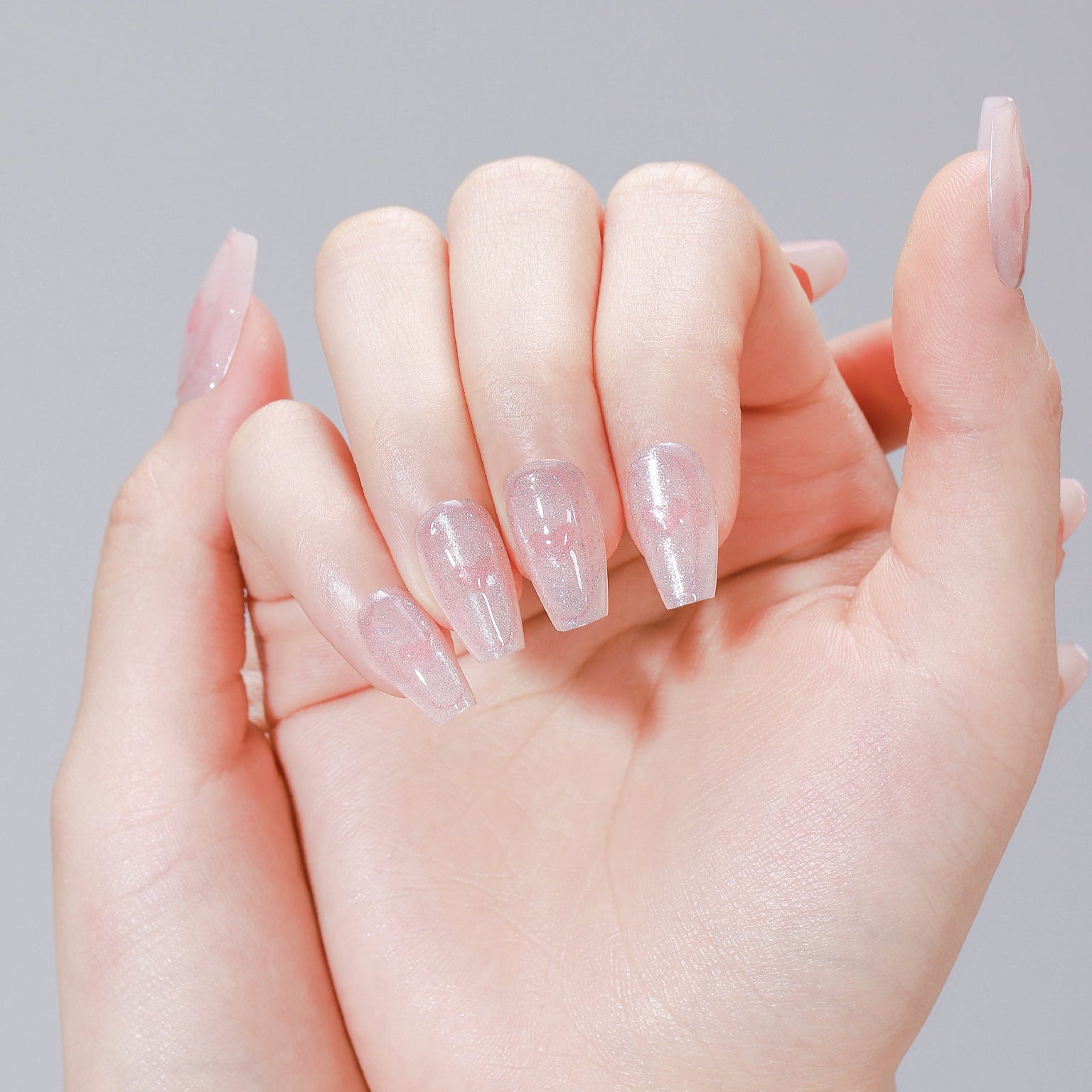 Hand wearing Cupid Glow pink heart glitter coffin press on nails with glossy finish