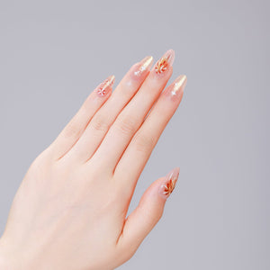 Close up of nude almond press on nails with gold firework bursts and white stars