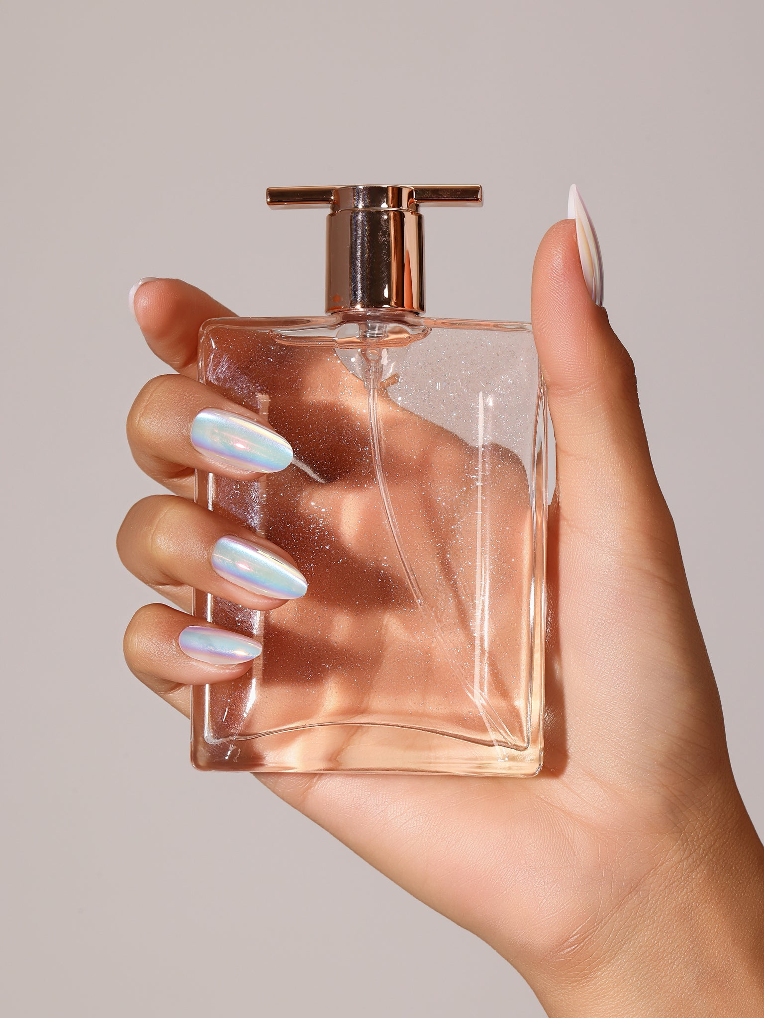 Hand wearing Crystal Fall iridescent holographic press on nails in a short to medium square shape