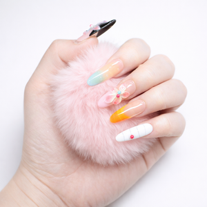 Hand model holding pink fluffy prop wearing long almond press on nails with 3D flower accent, pastel ombre tips, orange French tip and glossy finish