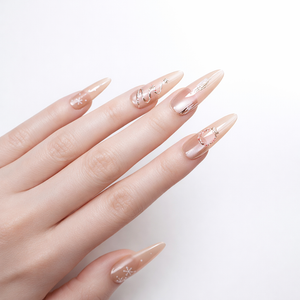 Elegant nude stiletto press on nails with gold wire and crystal details on a professional white skin model hand in studio lighting