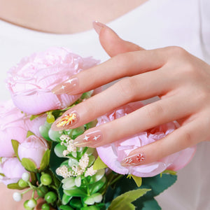 Close up of nude almond press on nails with gold firework bursts and white stars