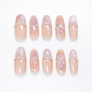 Soft blush almond press on nails with sheer nude base, pearly glitter tips, delicate pink floral accents, and micro pearl details in a full 10-nail set