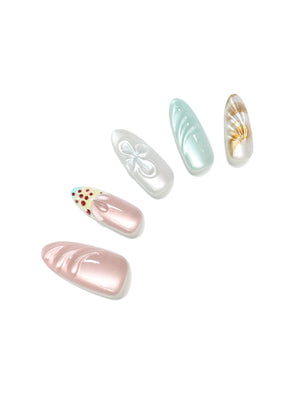 Close-up long almond pearly seashell press-on nails with sculpted shell ridges mint pearl accent and glossy finish