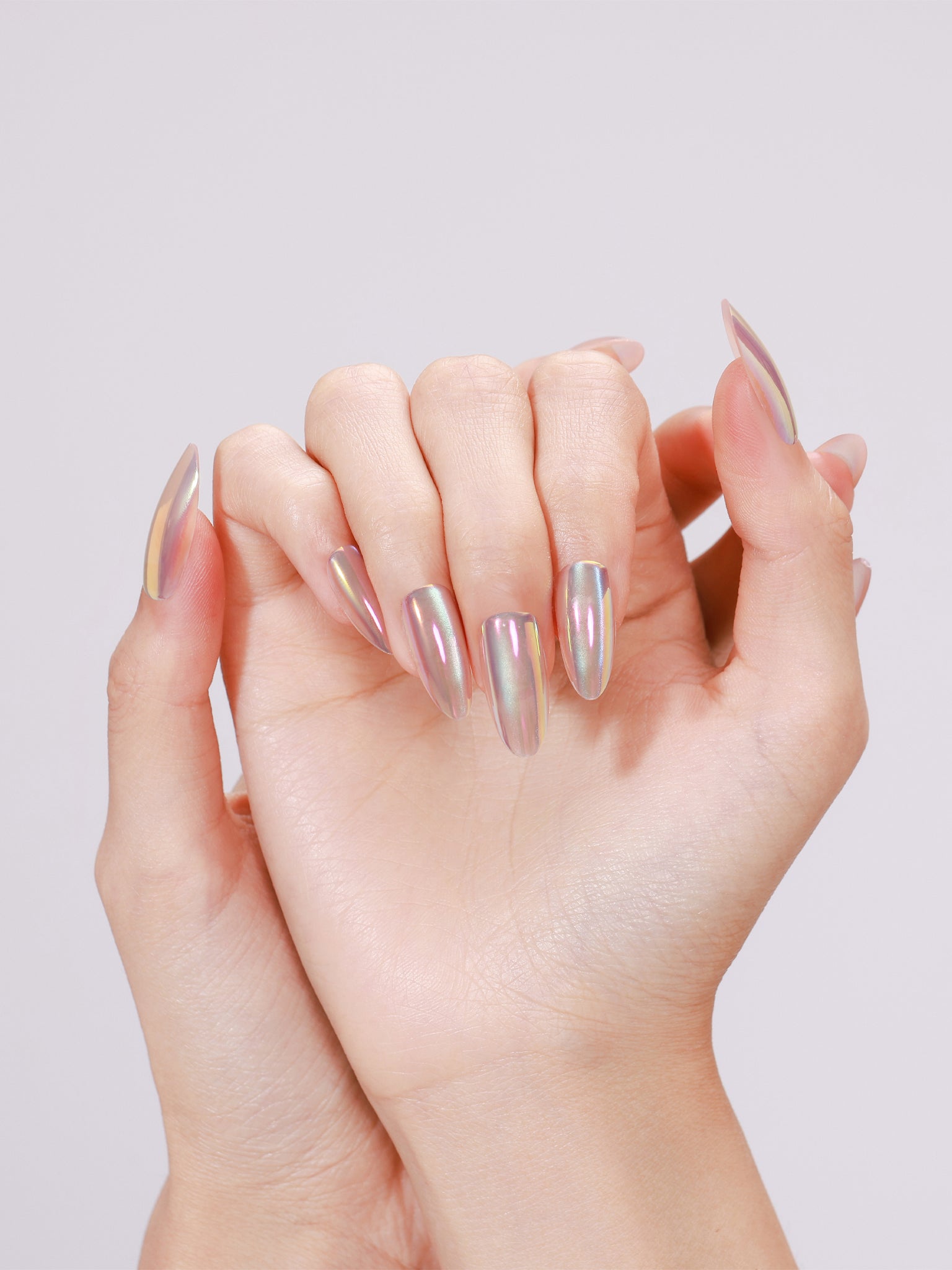Hands wearing Mirror Dust long almond mirror chrome press-on nails with rainbow shift