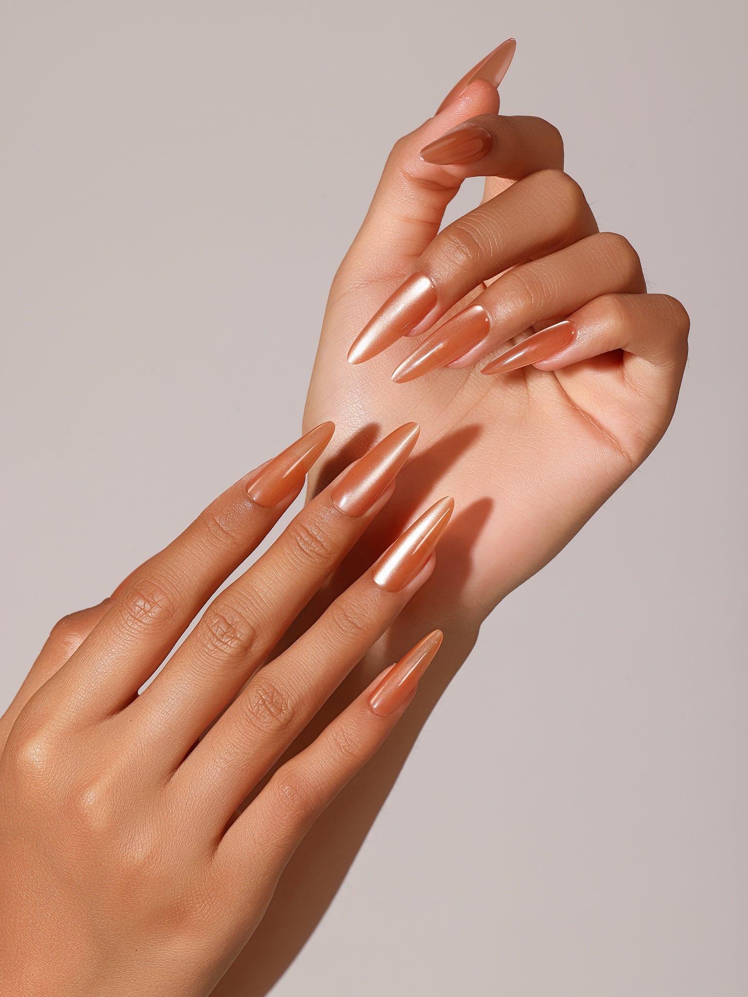 Hand wearing Citrus Crush long stiletto copper orange chrome press on nails reflective metallic manicure