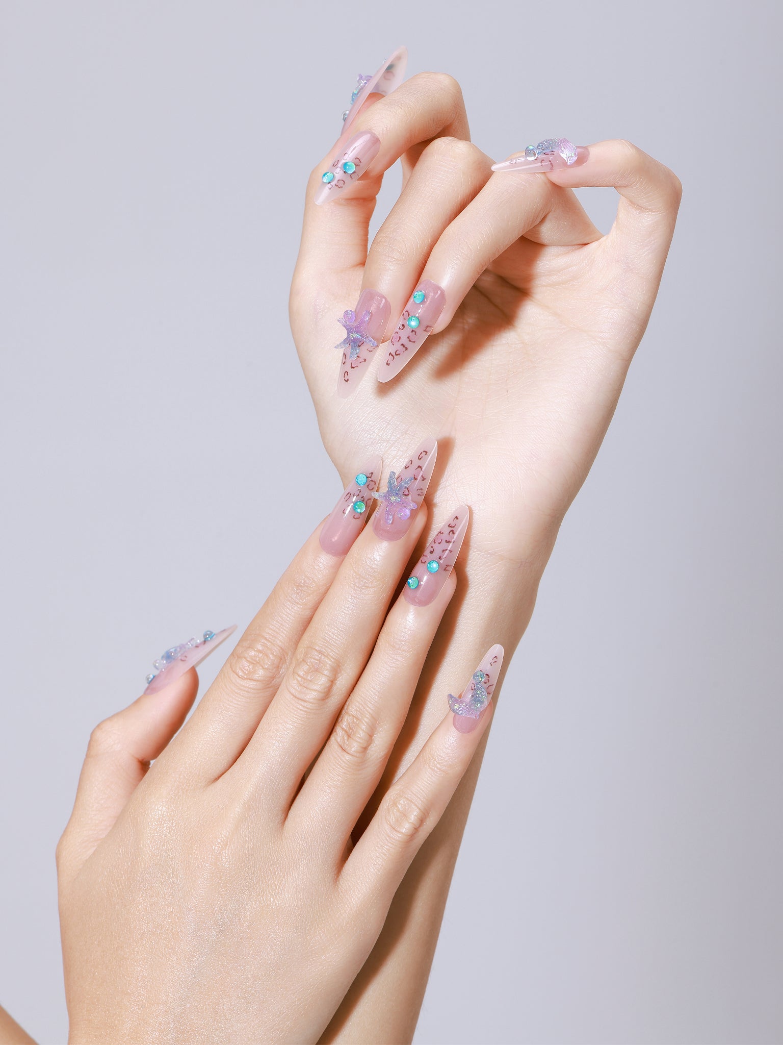 Hand wearing Star of the Tide long almond nude jelly press-on nails with turquoise gem accents
