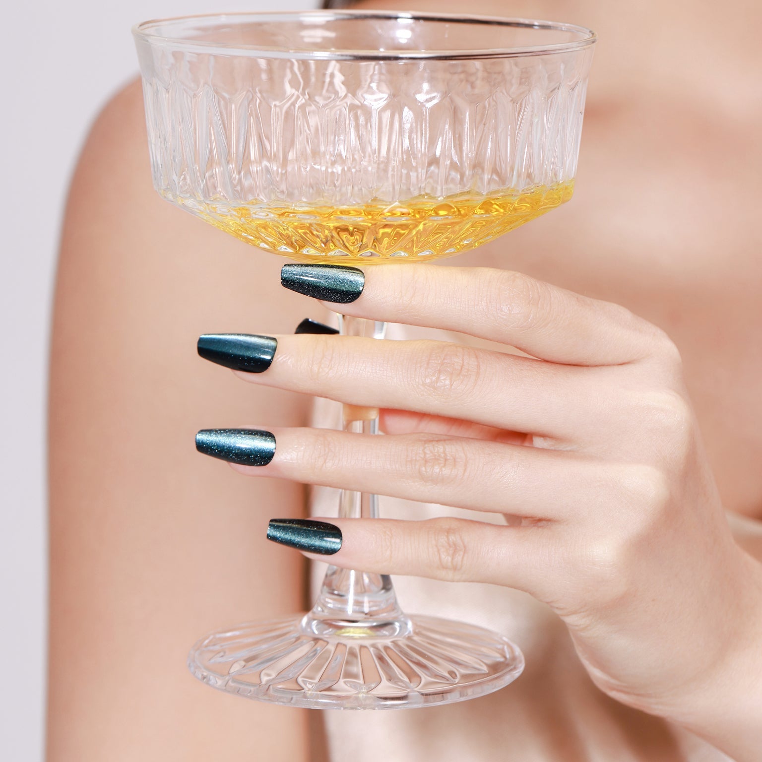 Hand holding champagne glass wearing Midnight Kiss long coffin midnight blue press-on nails