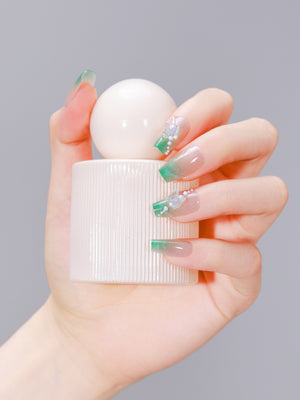 Hand holding perfume bottle wearing Garden Grace long coffin green French tip nails with 3D butterflies