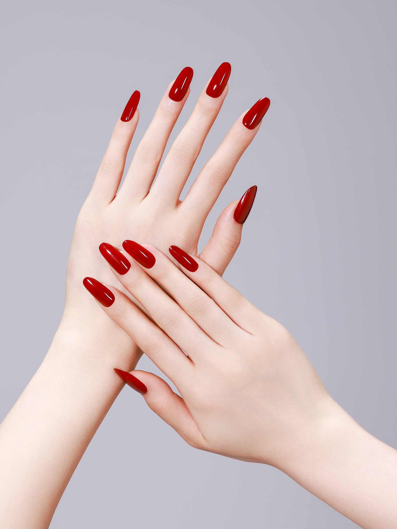 Hand wearing Fire & Desire fiery red long oval press on nails for bold, feminine manicure