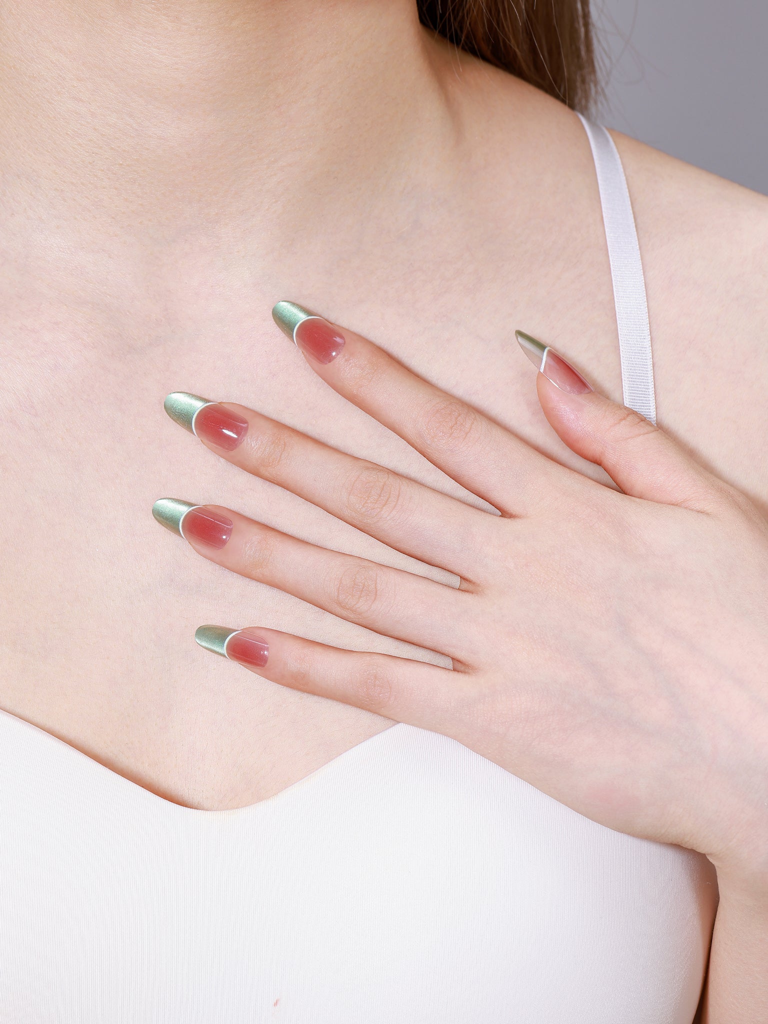 Close-up of Fresh Meadow long oval mint green French tip press-on nails on peach base