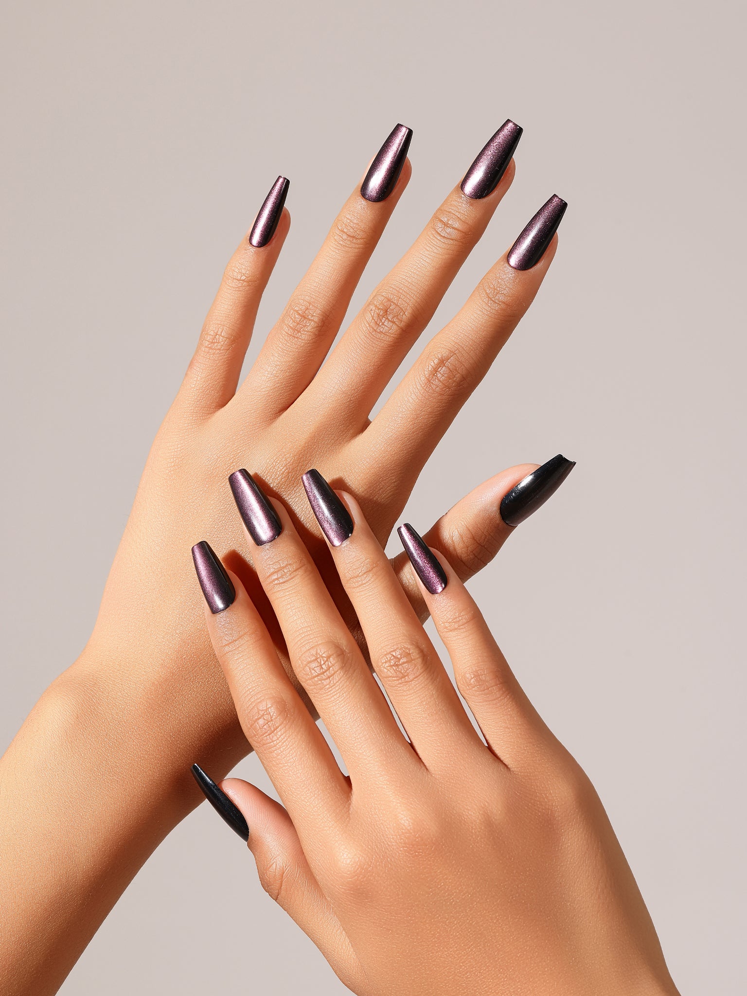 Close-up of hands with dark purple nail polish on a neutral background