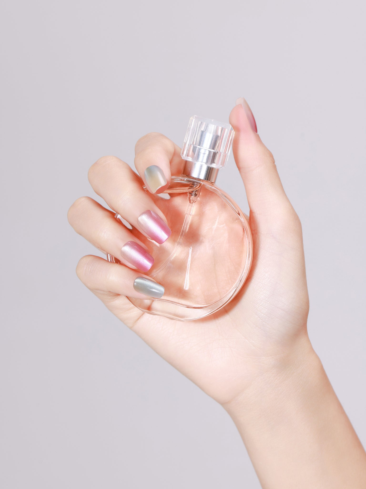 Hand holding perfume bottle wearing Crystal Candy short square chrome press-on nails 