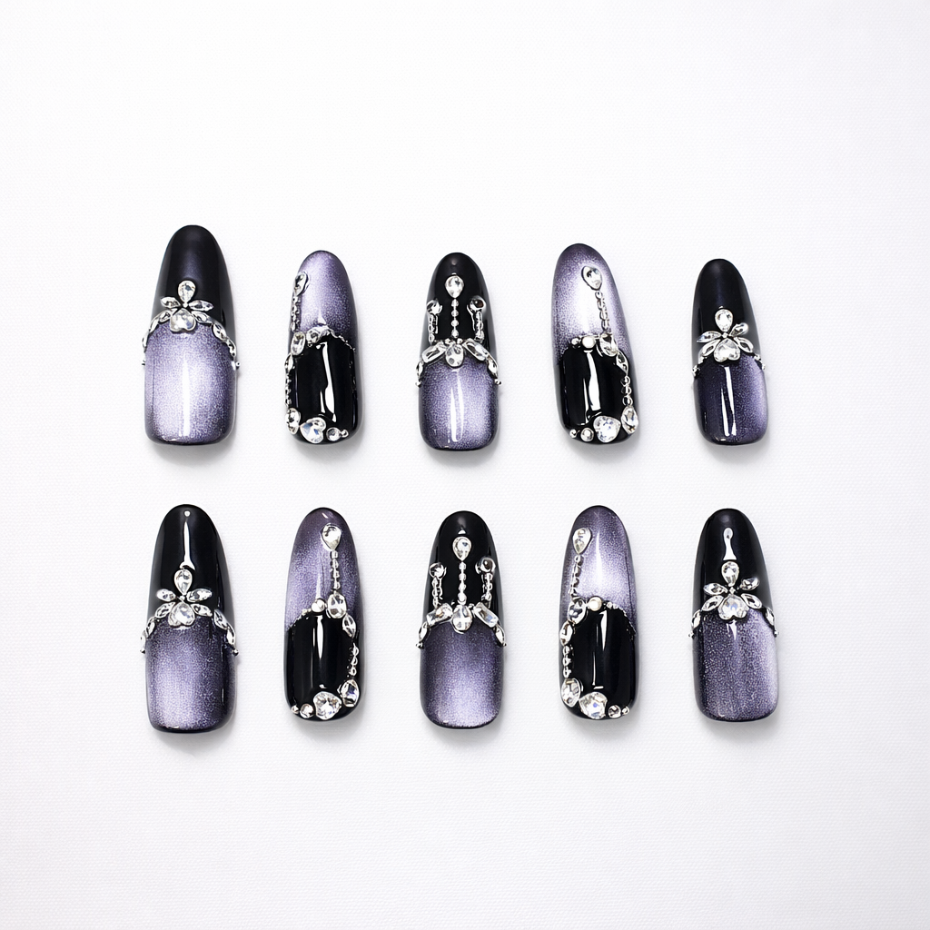 Black and purple cat-eye ombré almond press-on nails with glossy black tips, metallic violet shimmer, rhinestone chain accents, and crystal flower charm details.