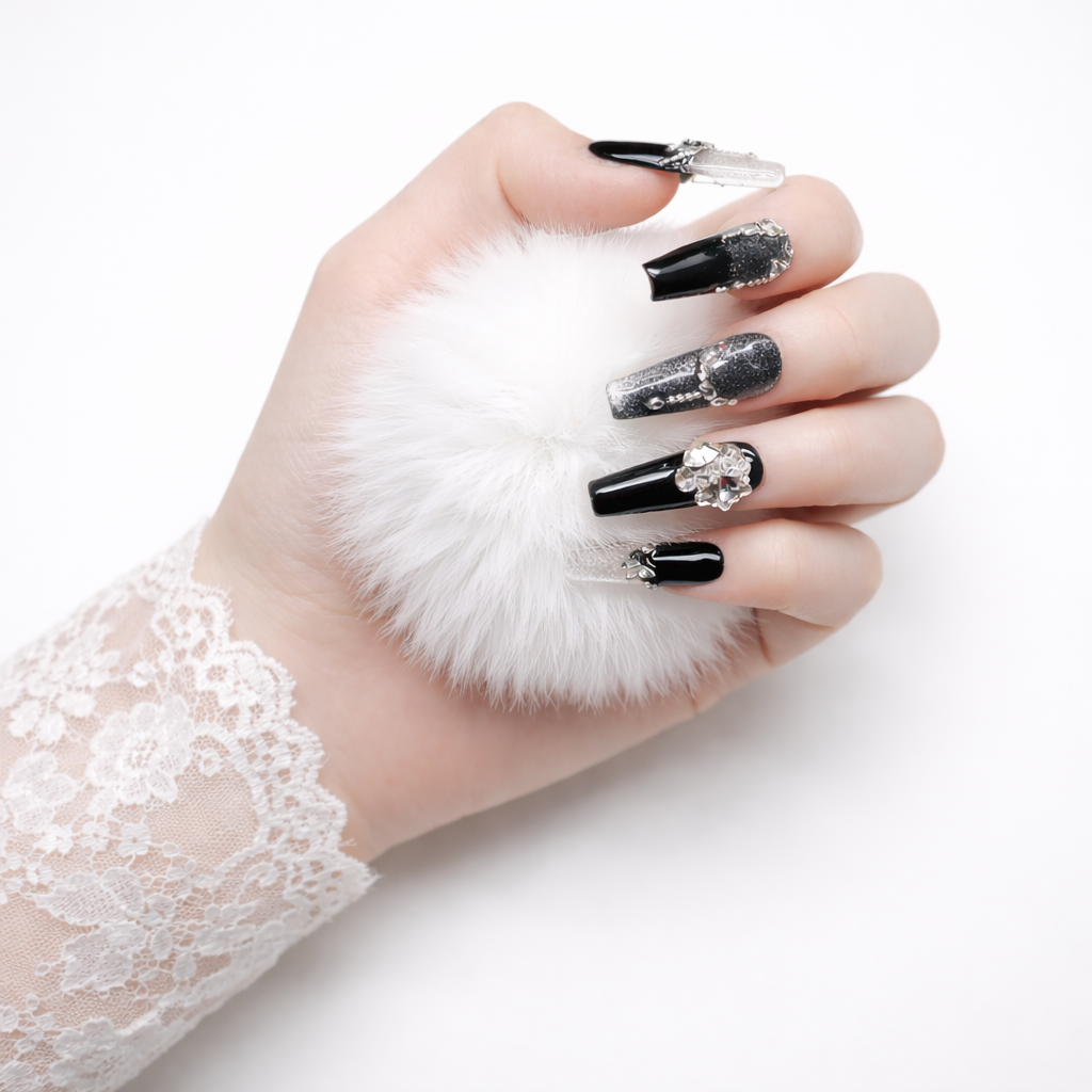 Hand model holding white pom pom wearing black and silver coffin press on nails with glitter accents, rhinestones and 3D crystal charm
