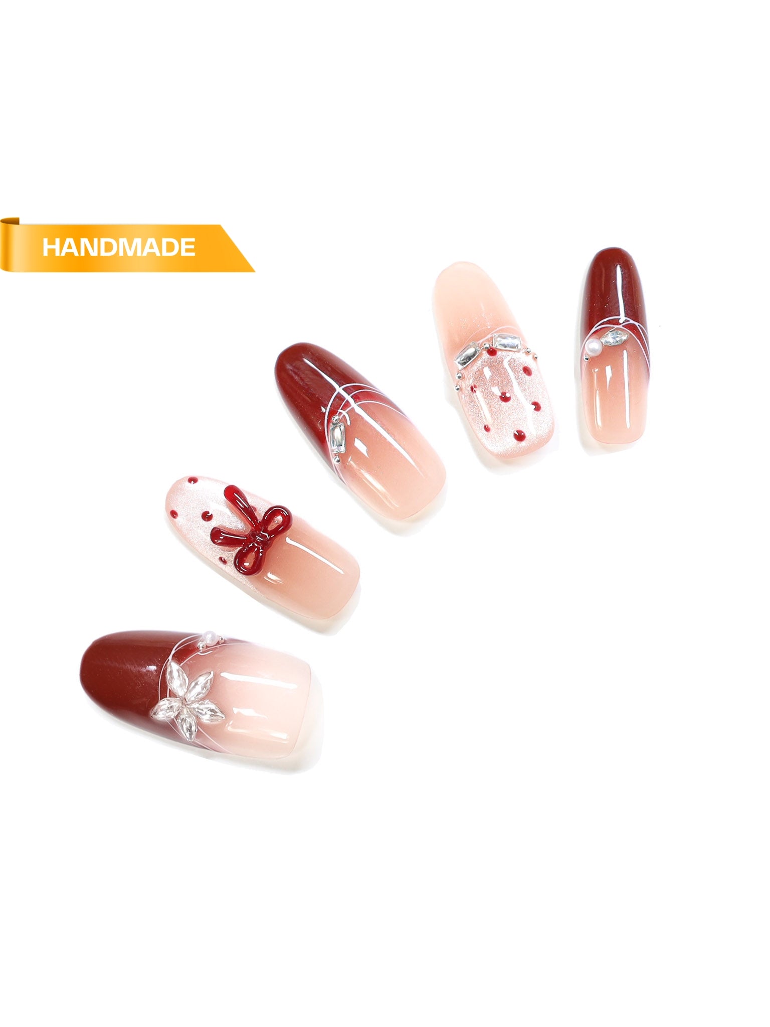 Handmade almond press-on nails in red and nude ombré with bow detailing, pearl accents, and rhinestones on white background