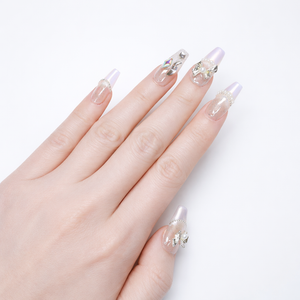 Coffin shaped press on nails with translucent glitter base, soft pearl chrome tips, pearl trim, and silver bow nail art worn on hand