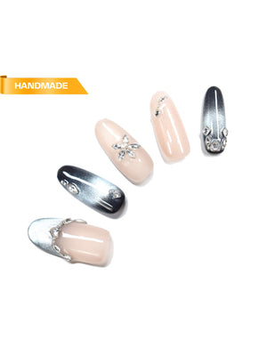 Handmade almond press-on nails in nude and silver chrome with rhinestone accents on white background